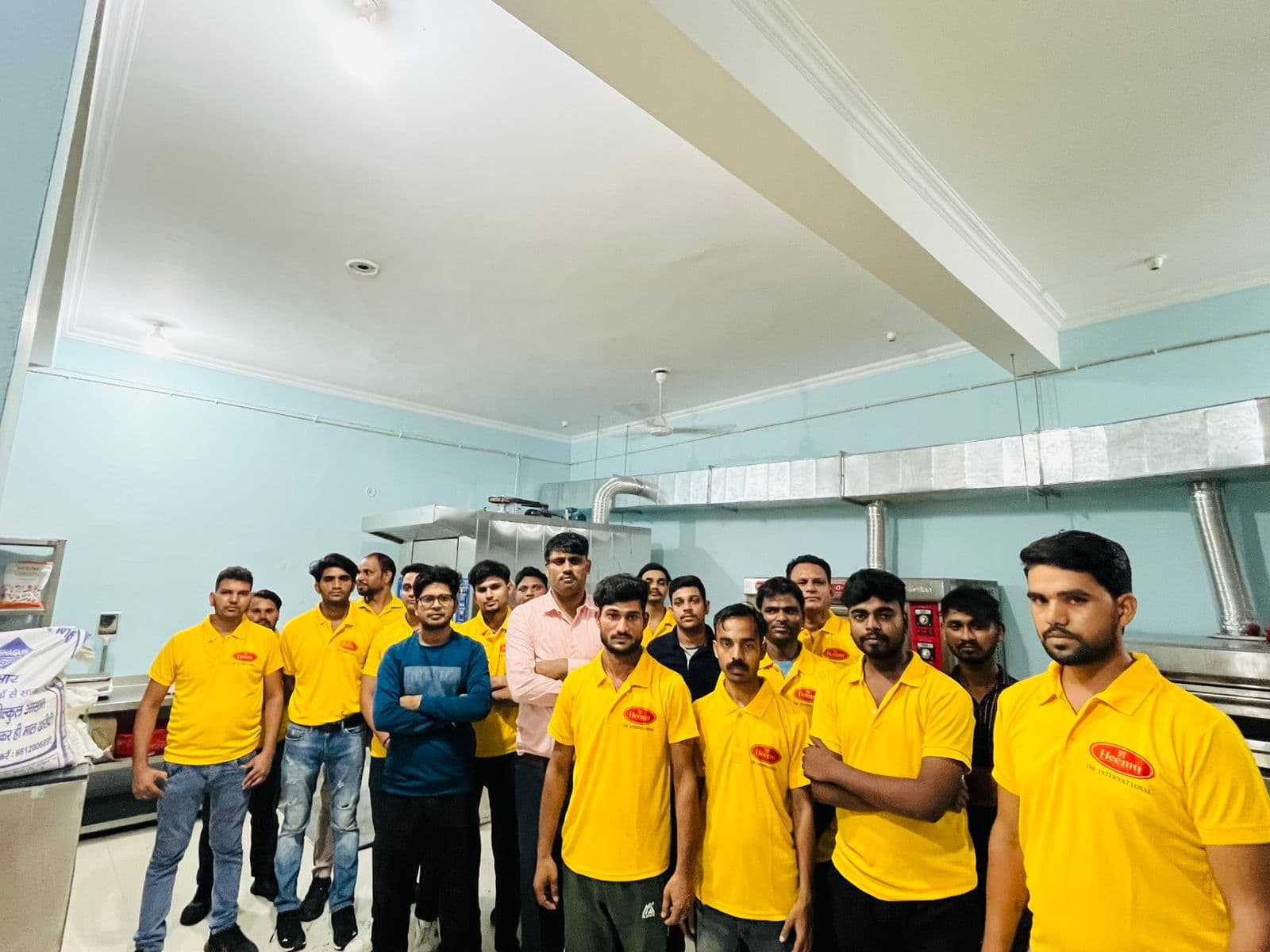 Large group of JBR production staff in yellow branded uniforms in the bakery kitchen