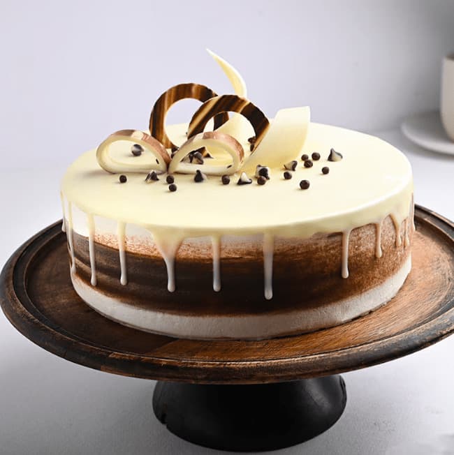 White chocolate drip cake with chocolate curls over a marbled chocolate-vanilla base
