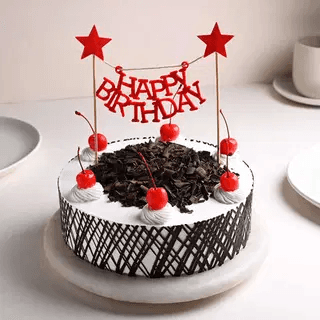 Black Forest birthday cake with chocolate shavings, cherries and a Happy Birthday topper